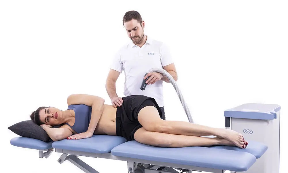 Anwendung des BTL-Kryo durch Therapeuten an der Hüfte einer Frau auf einer Therapieliege