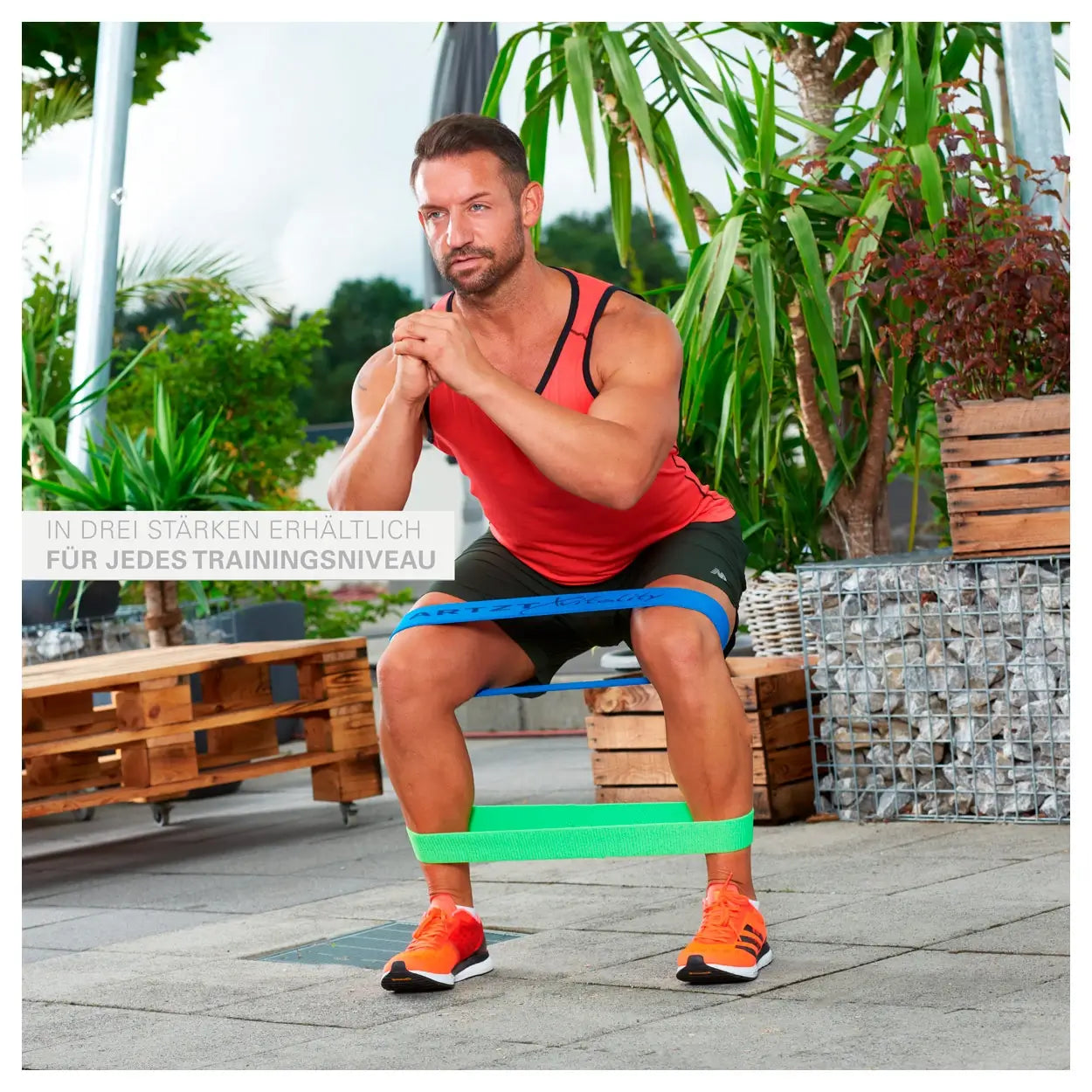 Mann macht Kniebeugen mit Loop-Bändern ARTZT vitality in blau und grün