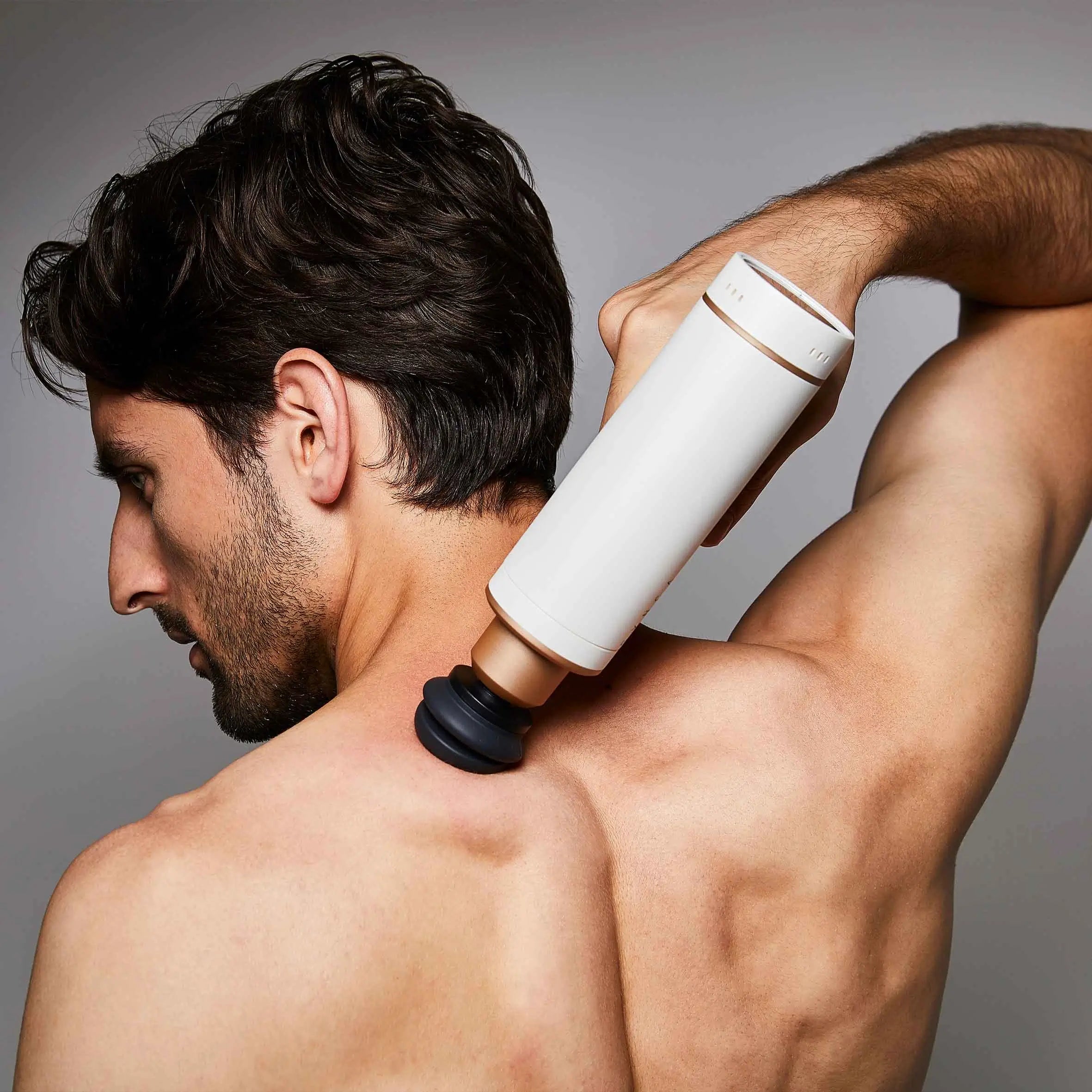 Mann massiert den Nacken mit der Faszien-Massagepistole Synca Kitta