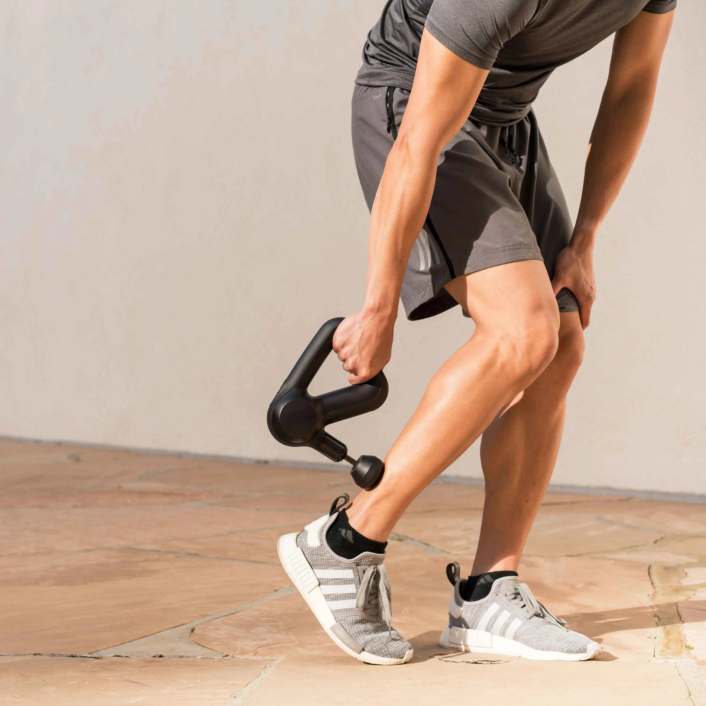 Mann massiert sich den Unterschenkel mit dem Faszien-Massagegerät Theragun Prime