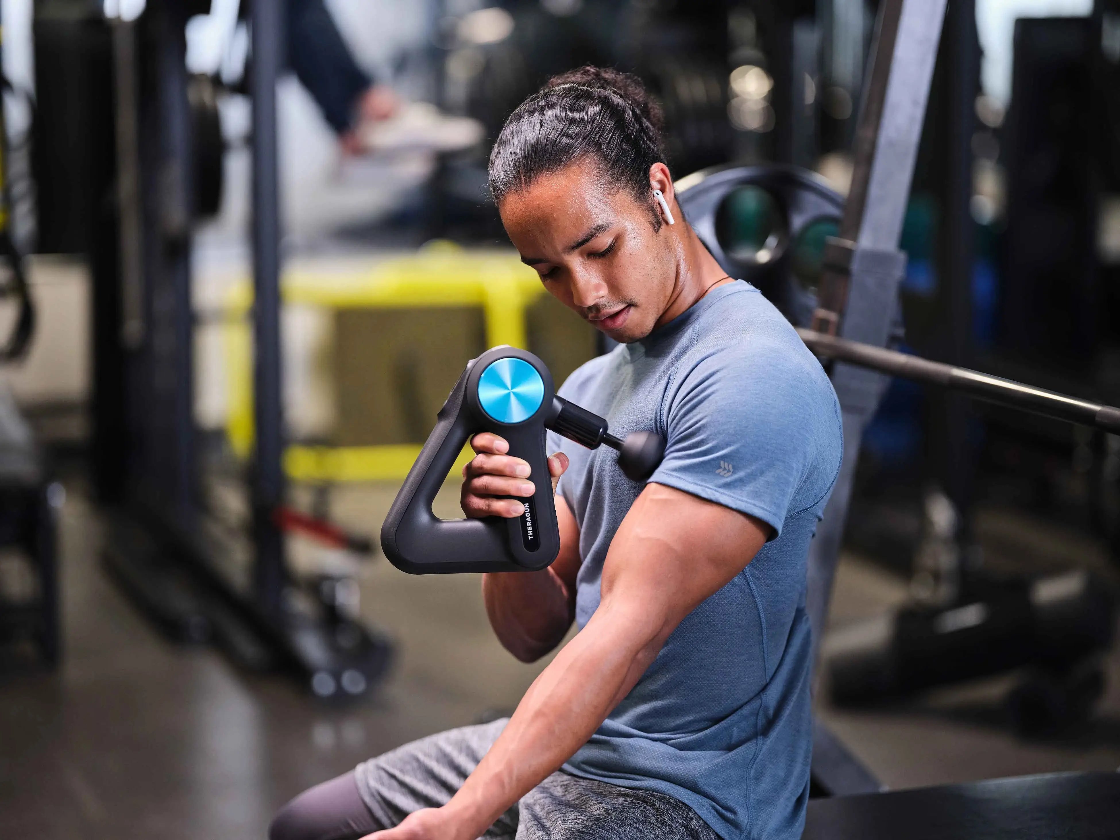 Mann massiert Brustansatz mit Massagegerät Theragun Pro