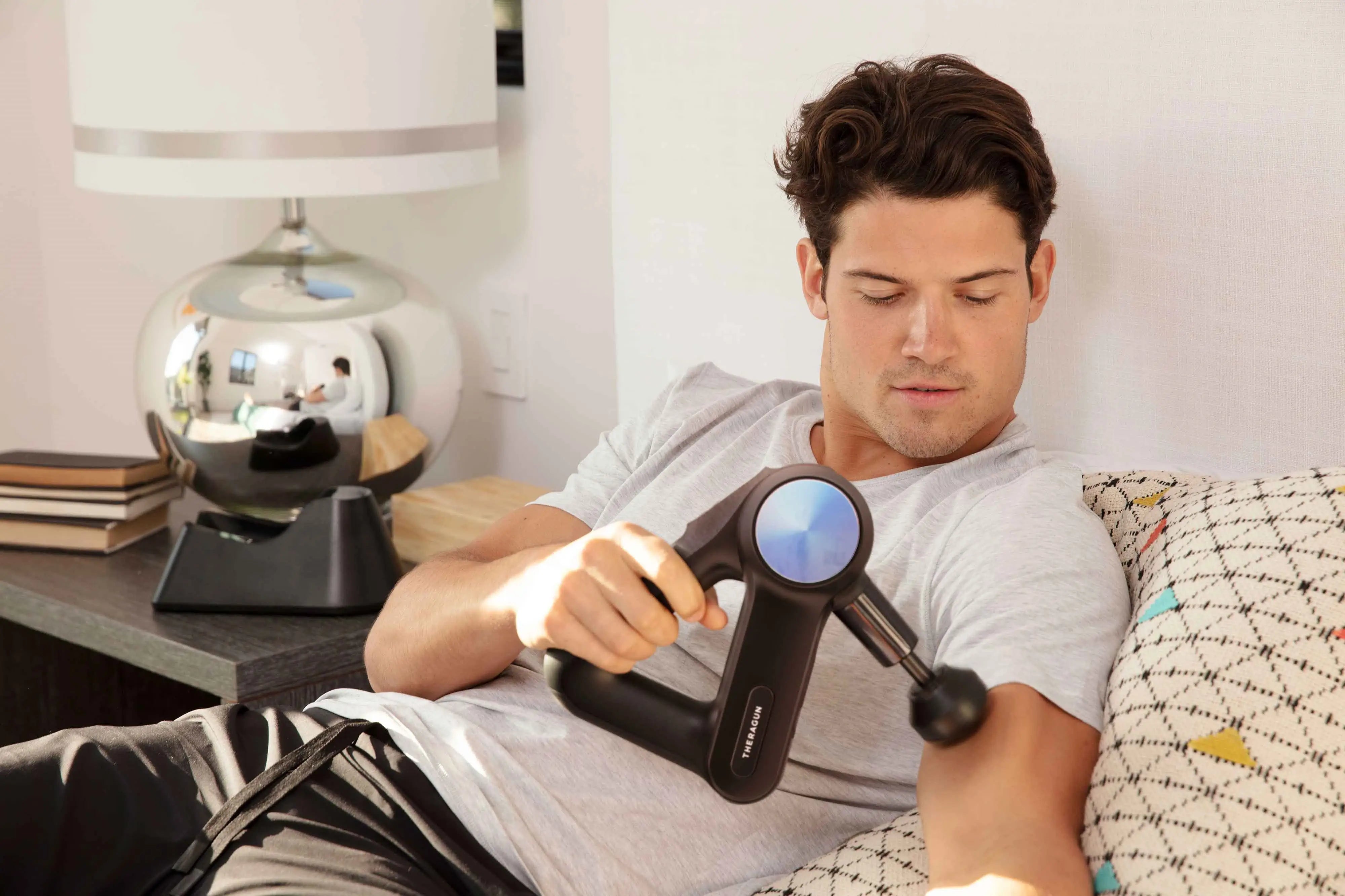 Mann massiert Bizeps mit Massagegerät Theragun Pro