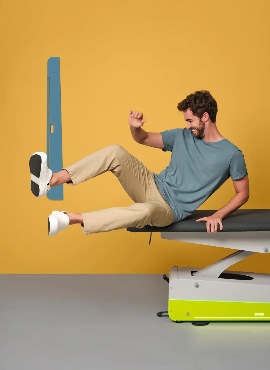 Glücklicher Patient in Actionpose auf dem Fußteil der Therapiebank Naggura Swop 2 Pro