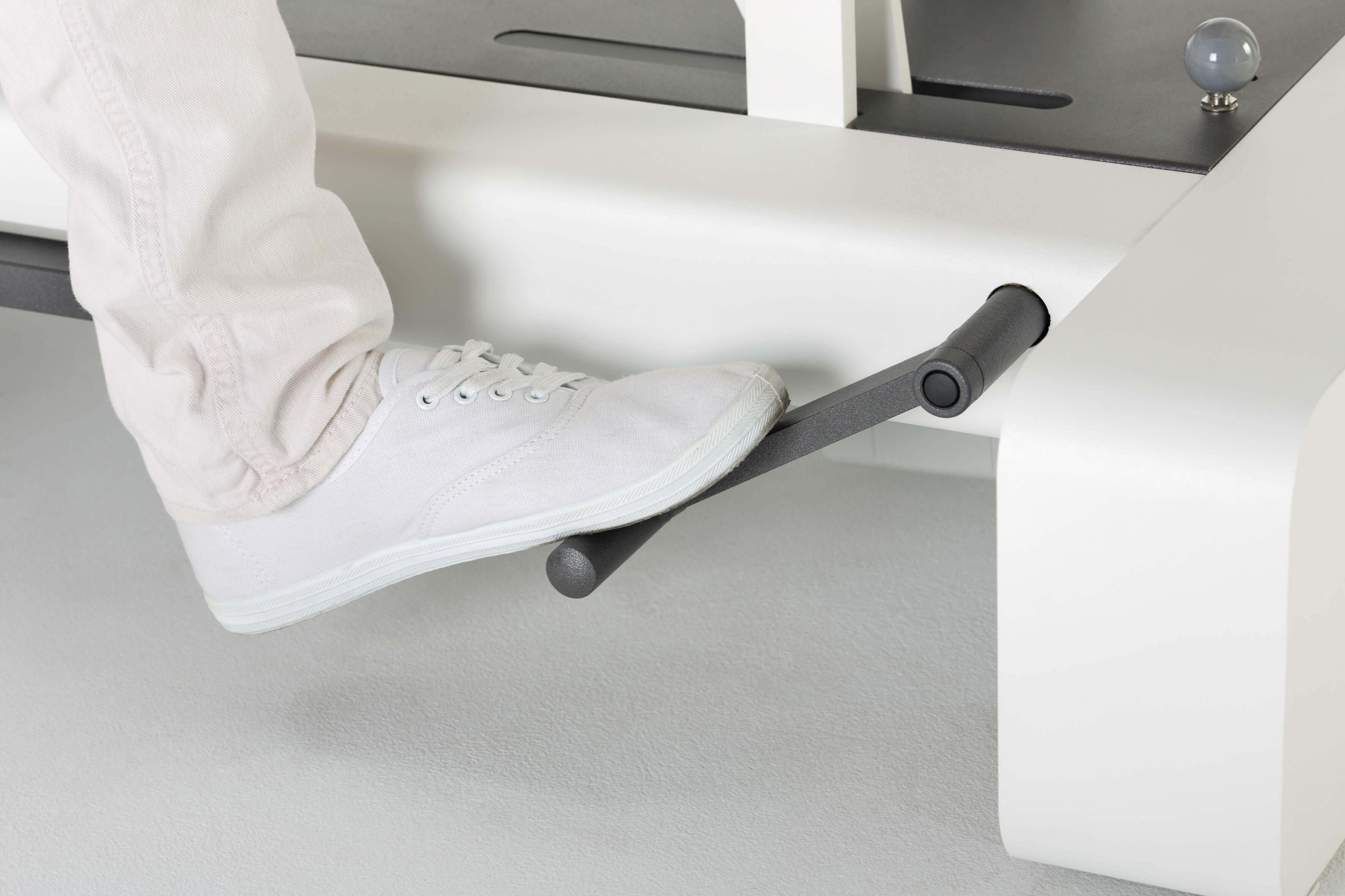 Therapeut betätigt Höhenverstellung mit Fuß an der hydraulischen Behandlungsliege NEXX 3