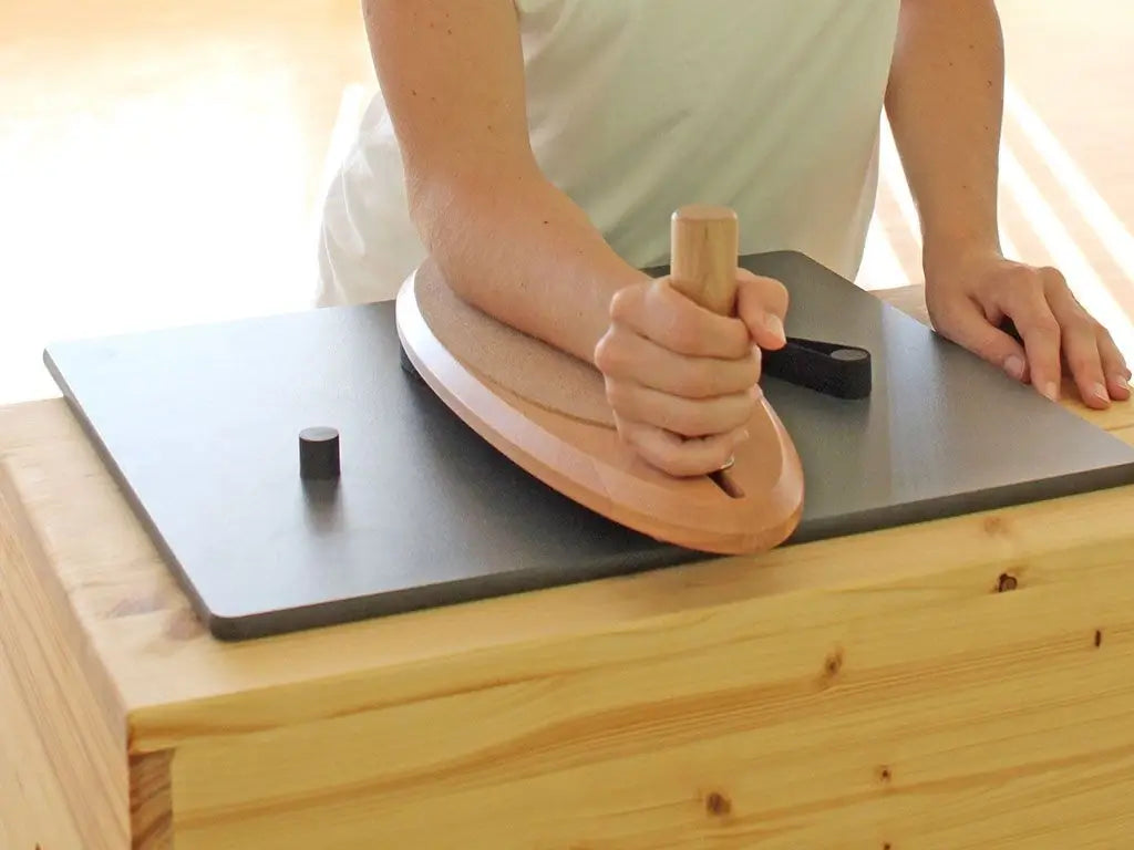 Person trainiert Schulter mit Pedalo PhysioFlip auf einem Tisch