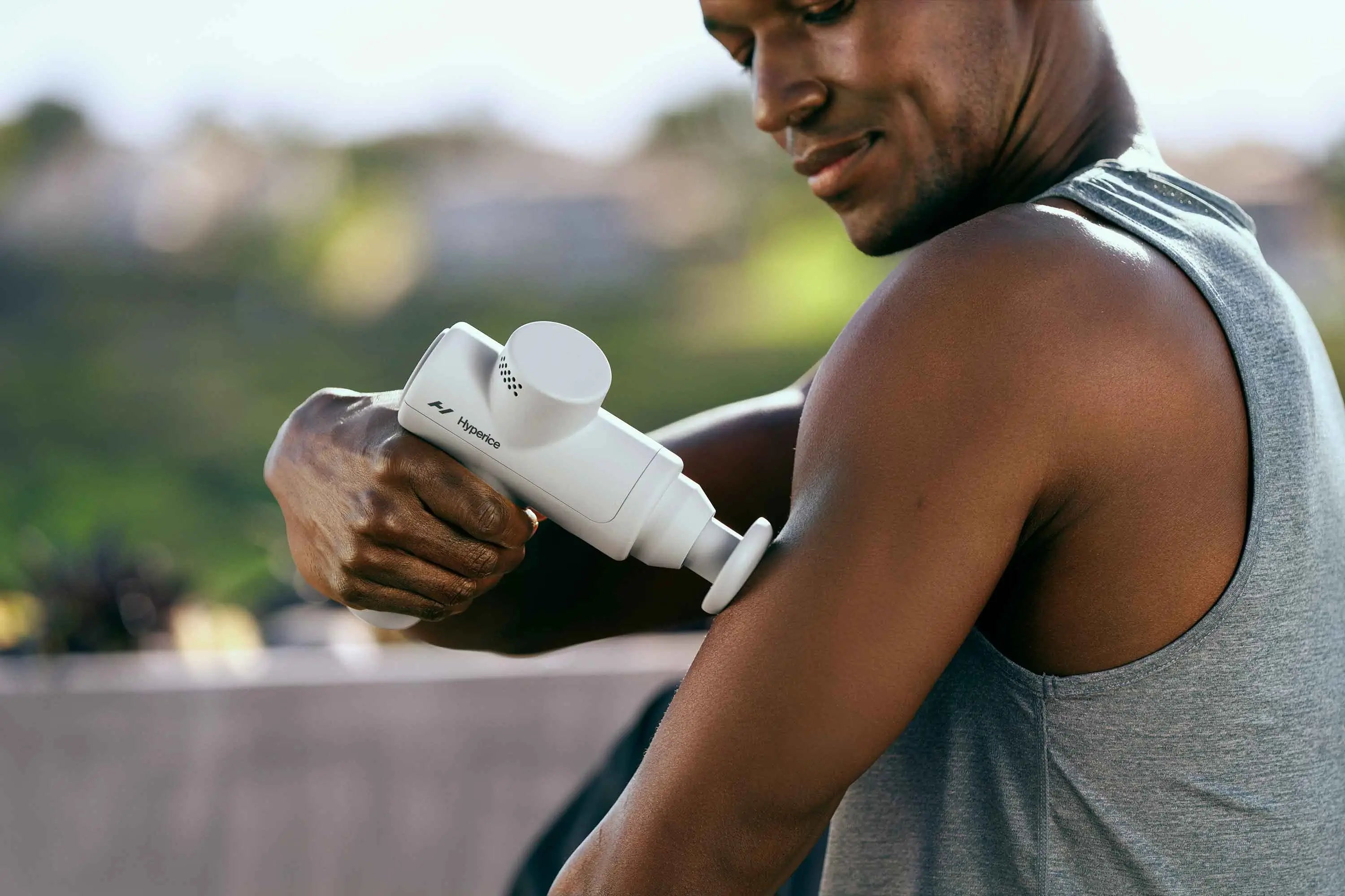 Mann massiert Trizeps mit Gun-Massagegerät Hyperice Hypervolt Go 2