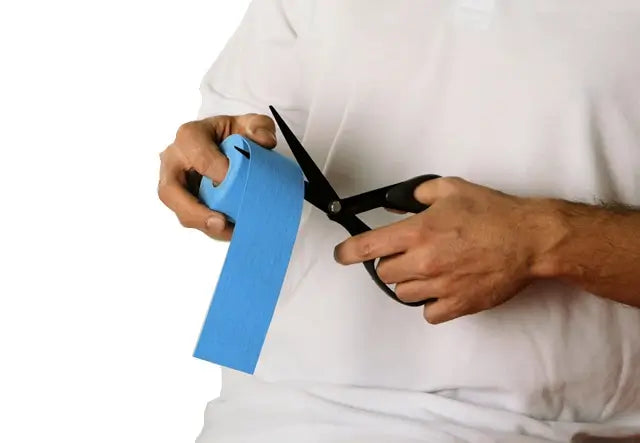 Mann schneidet blaues Sporttape mit Kinesio-Tape-Schere K-Active® K Scissors K210 von Rolle ab