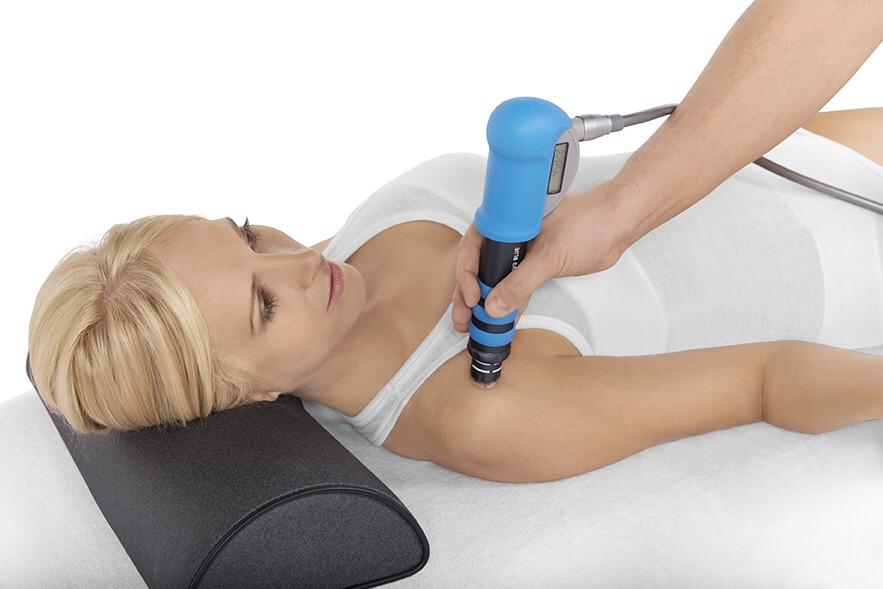 Applikator des radiales Stoßwellengerät SWISS DOLORCLAST® smart 20hz in Anwendung an der Schulter einer Frau
