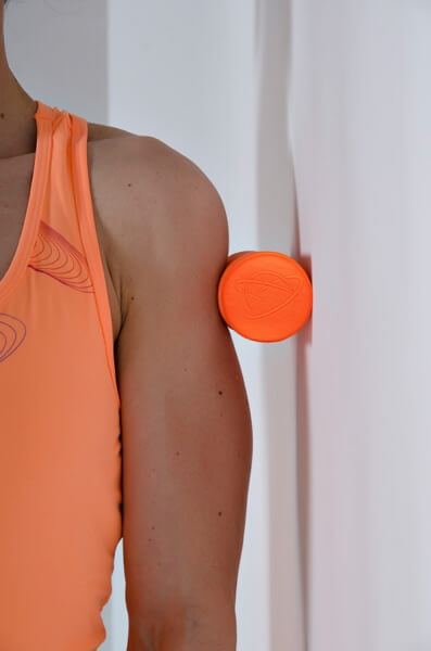Verwendung der Mini Faszienrolle Orange an der Schulter an einer Wand